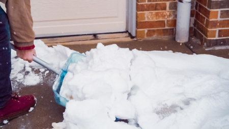 Young man shoveling snow from driveway.