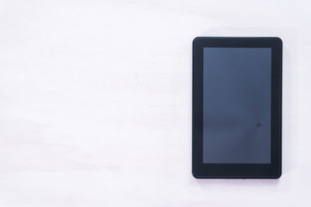 Black electronic book reader on a white table.