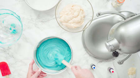 Step by step. Flat lay. Mixing food coloring into a cake batter to bake a three-layer vanilla cake.