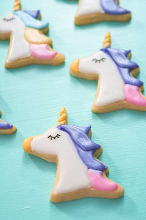 Unicorn sugar cookies decorated with royal icing and food glitter on a blue background.の写真素材