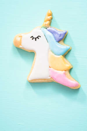 Unicorn sugar cookies decorated with royal icing and food glitter on a blue background.の写真素材
