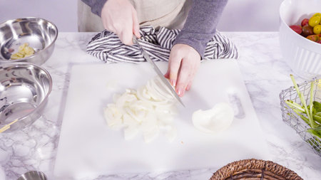 Step by step. Cutting vegetables on a white cutting board to make a one-pot pasta recipe.