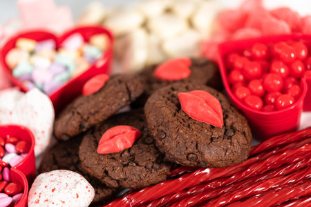 Valentines Day cheese board with a variety of cookies and candies.