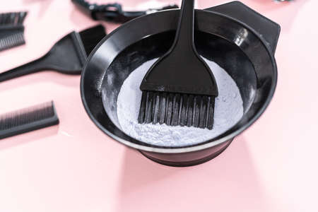 Hair color dye powder in a black plastic mixing bowl on a pink background.の写真素材