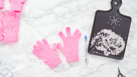Flat lay. Rhinestone pink kids gloves with snowflake shapes.