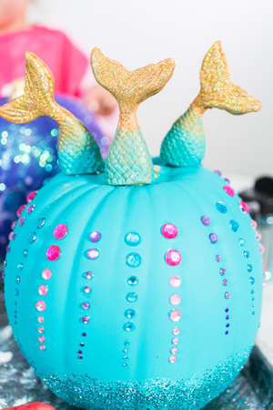 Little girl decorating her Halloween pumpkin with glitter.の写真素材