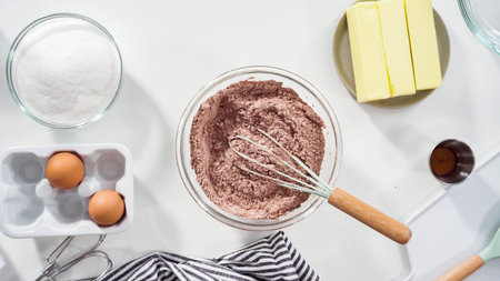 Step by step. Flat lay. Mixing ingredients in a glass mixing bowl to bake chocolate cookies.