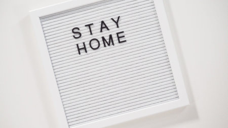 Flat lay. STAY HOME and STAY SAFE sign on message board with a homemade face mask.