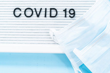 COVID-19 sign on message board with a blue medical mask.