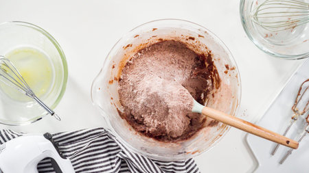 Step by step. Flat lay. Mixing ingredients in a glass mixing bowl to bake chocolate cookies.