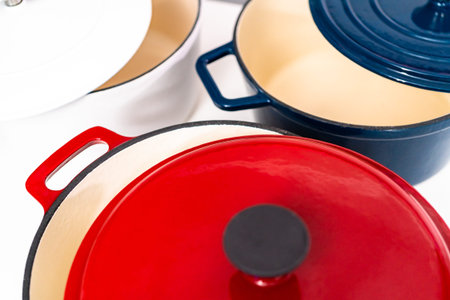 Red, white and blue enameled cast iron covered round dutch ovens on a whjite background.