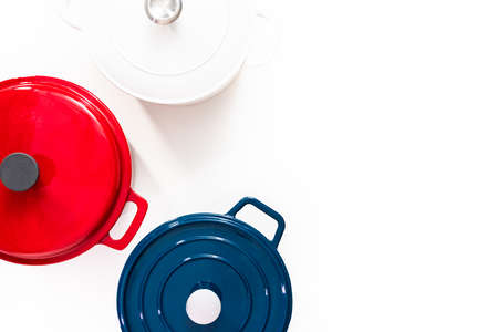 Red, white and blue enameled cast iron covered round dutch ovens on a white background.の写真素材
