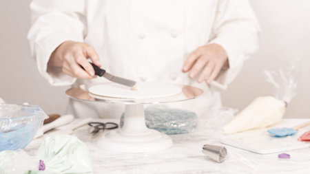 Stacking cake layers to create the round three-layer vanilla cake.