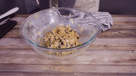 Step by step. Mixing ingredients to bake oatmeal raising cookies in a glass mixing bowl.