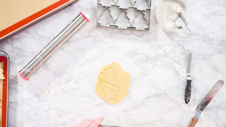 Flat lay. Cutting out sugar cookies with giant Christmas cookie cutter.