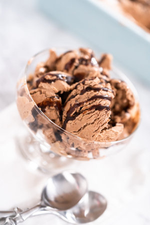 Serving homemade chocolate chip ice cream drizzled with chocolate in a glass bowl.