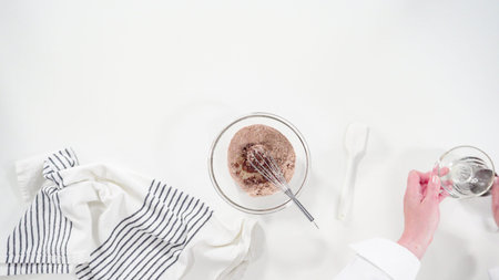 Flat lay. Mixing ingredients in a glass bowl to prepare glace for homemade cinnamon rolls.