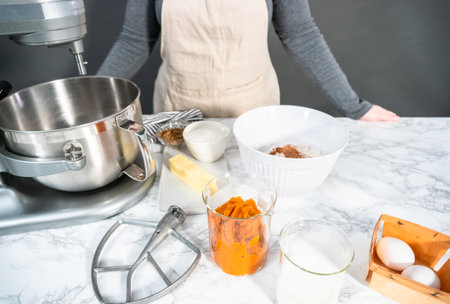 Ingredients to bake pumpkin spice cupcake on a marble countertop.の写真素材