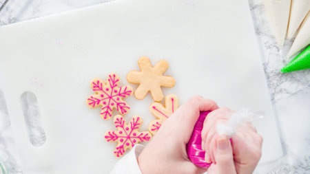 Flat lay. Stp by step. Icing snowflake shaped sugar cookies with pink icing.