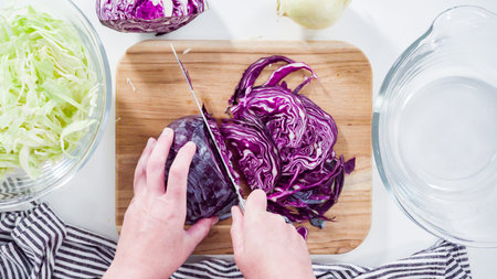 Flat lay. Step by step. Shredding organic cabbage on a wood cutting board.