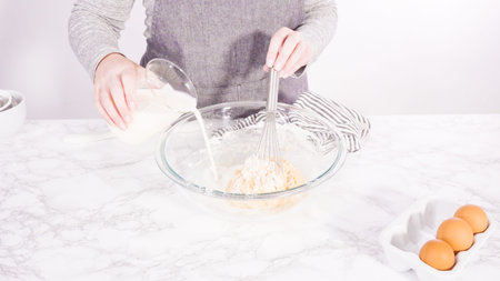 Mixing ingredient in a glass mixing bowl to make the crepes batter.