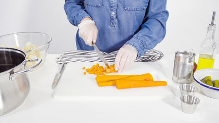 Step by step. Cutting cookies vegetables on a white cutting board for vinaigrette salad.の写真素材