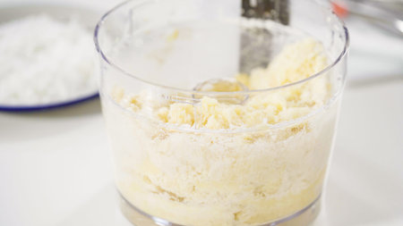 Mixing ingredients in a food processor to prepare homemade coconut cookies.