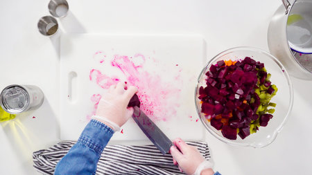 Flat lay. Step by step. Cutting cookies vegetables on a white cutting board for vinaigrette salad.