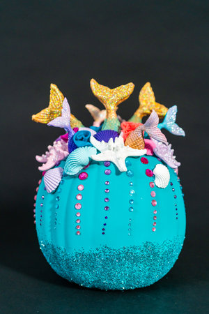 Halloween craft pumpkins decorated with mermaid tails, glitter, and sparkly rhinestones on a black background.の写真素材