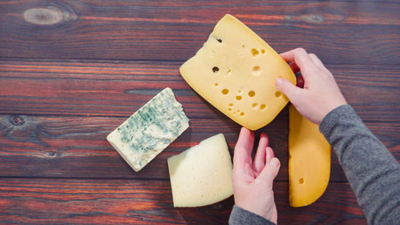Flat lay. Large wedges of gourmet cheese on a rustic wood background.の写真素材