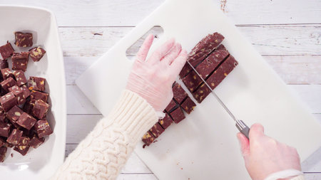 Flat lay. Step by step. Cutting homemade macadamia fudge on a white cutting board.
