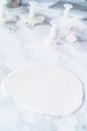 Rolling out fondant to cut snowflake shapes with cookie cutters.の写真素材