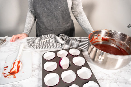 Lining cupcake pan with cupcake liners to bake red velvet cupcakes.