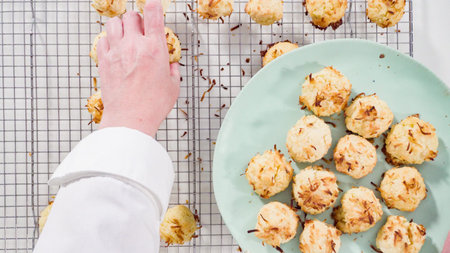 Flat lay. Putting freshly baked coconut cookies on a serving plate.の写真素材