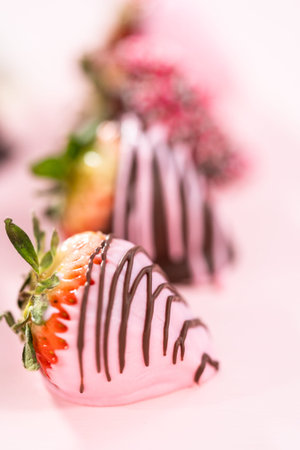 Variety of chocolate dipped strawberries on a pink background.