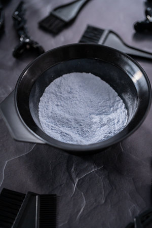 Hair color dye powder in a black plastic mixing bowl on a black background.の写真素材