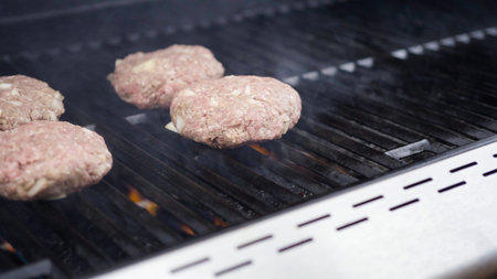 Cooking hamburger beef patties on a gas grill.