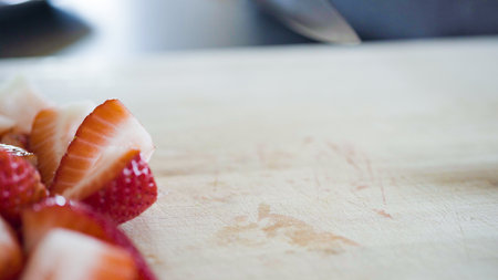 Slicing fresh strawberries on a wood cutting board.の写真素材