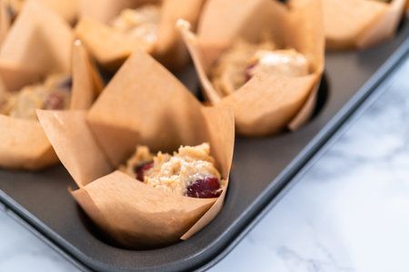 Scooping dough into muffin cups to bake cranberry muffins.の写真素材