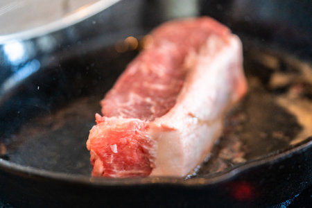 Frying New York strip steak in cast iron frying pan over the electric stove.の写真素材