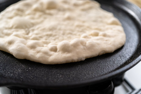 Preparing homemade flatbread on a cast-iron skillet.の写真素材