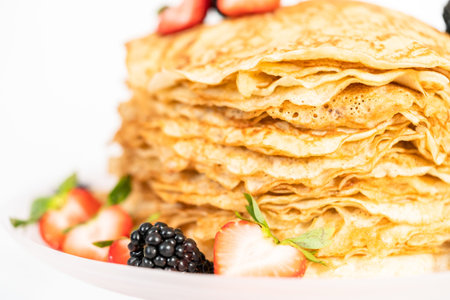Close up. Stack of freshly baked crepes with berries on a cake stand.