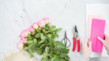 Flat lay. Step by step. Florist arranging a bouquet from pink roses.の写真素材