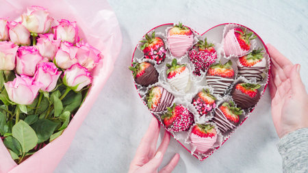 Flat lay. Step by step. Bouquet of pink roses with a box of chocolate dipped strawberries.の写真素材