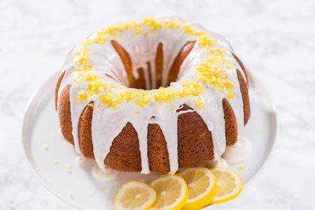 Lemon bundt cake decorated with lemon zest on a cake stand.の写真素材
