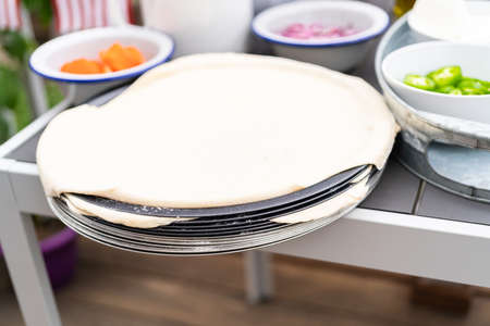 Pizza dough and ingredients for grilling pizza on an outdoor gas grill.の写真素材