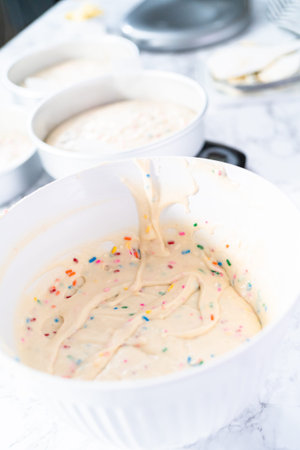 Mixing ingredients to bake birthday funfetti cake with colorful sprinkles.
