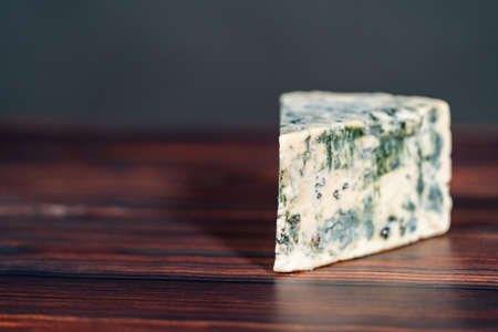 Large wedge of blue cheese on a dark wooden background.の写真素材