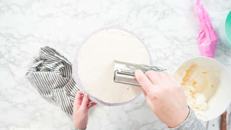 Flat lay. Step by step. Frosting round funfetti cake with white italian buttercream frosting.の写真素材