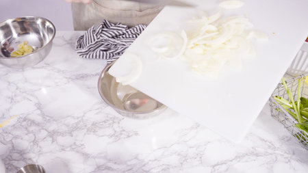 Step by step. Cutting vegetables on a white cutting board to make a one-pot pasta recipe.